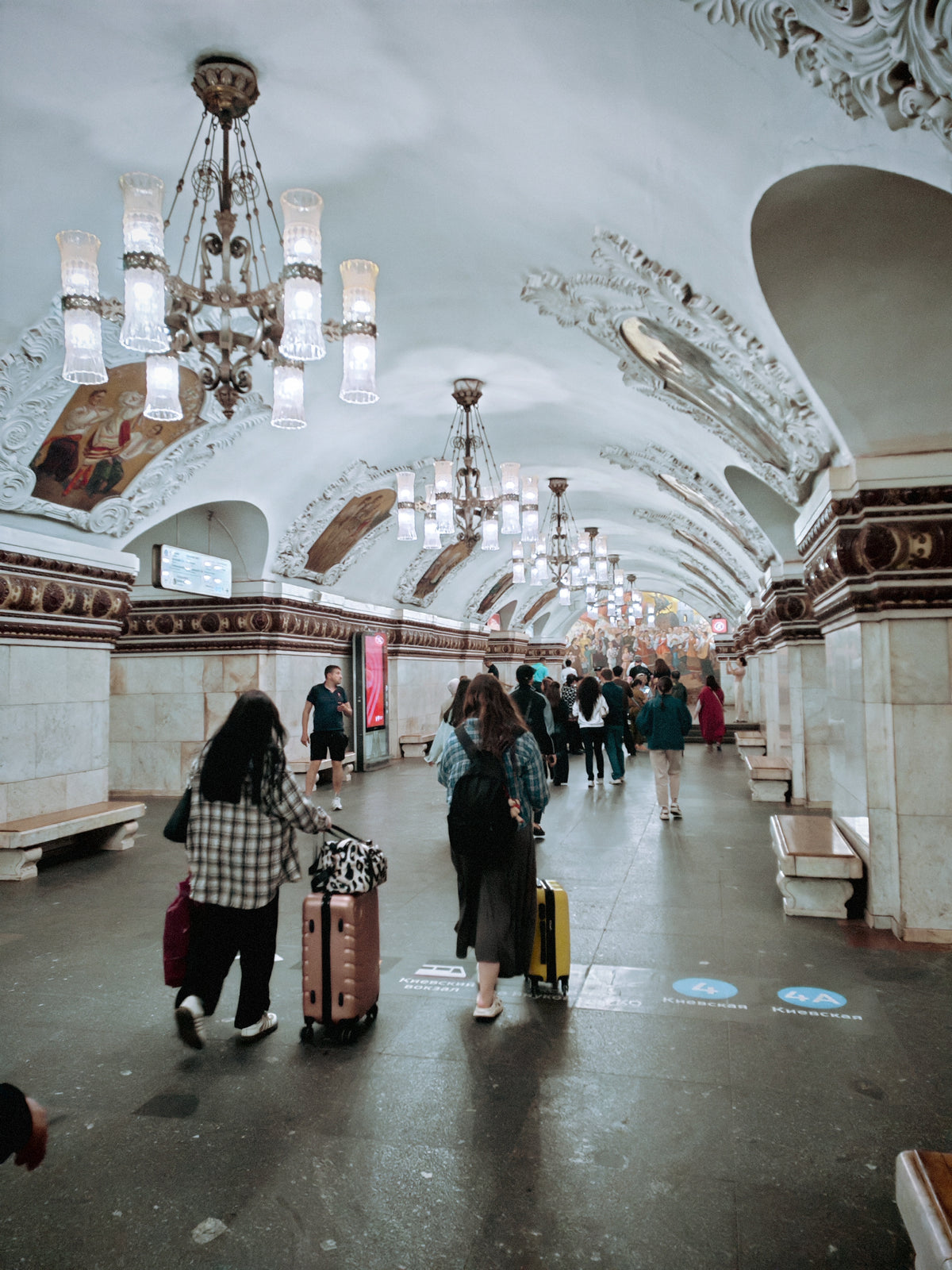 Világos márványburkolatú állomáscsarnok a moszkvai metróban.
