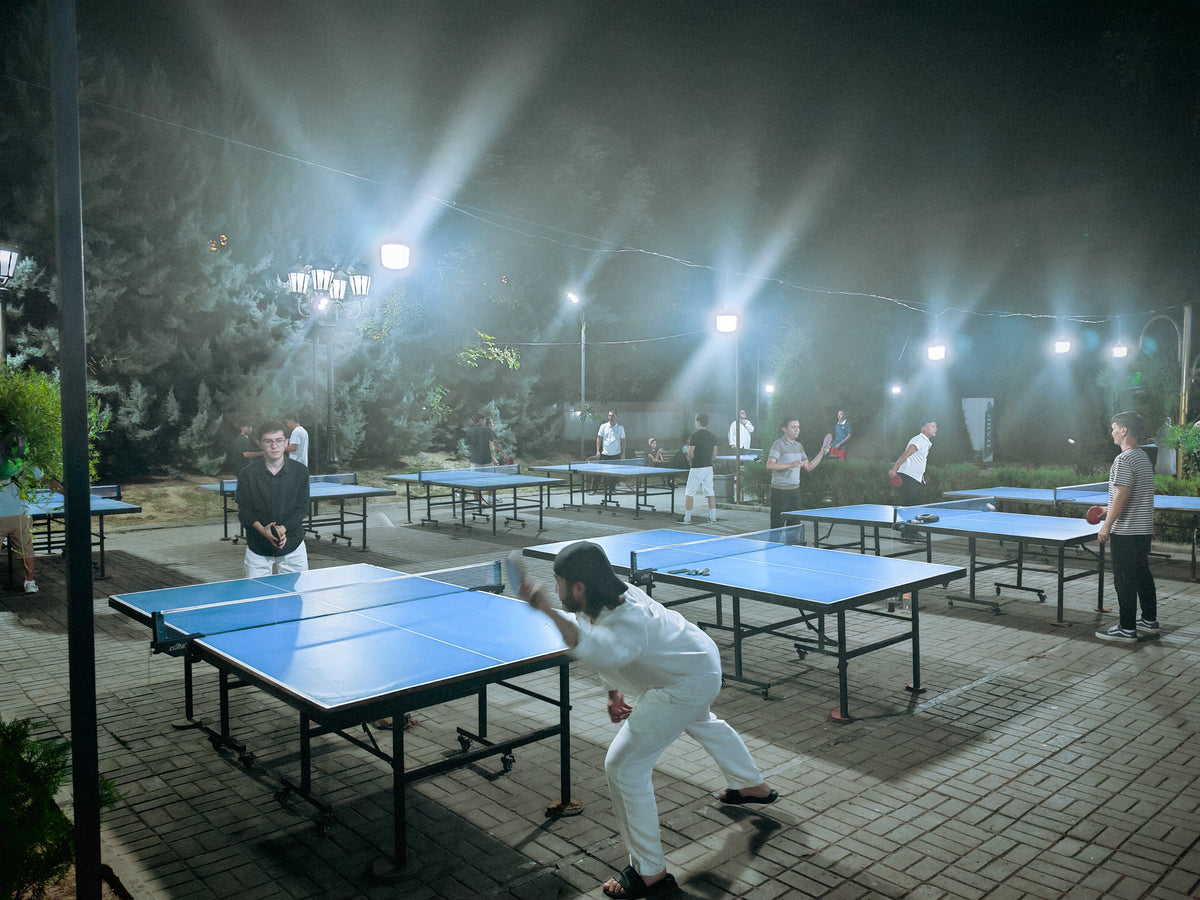 Szabadtéri pingpongasztalok és játékosok Taskentben éjszaka.