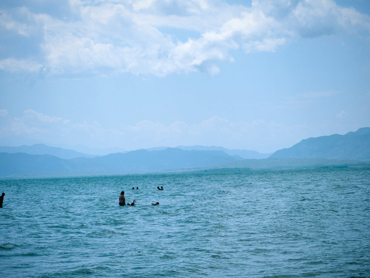 Fürdőző az Issyk-Kul vizében, a távoli hegyvonulat előtt.