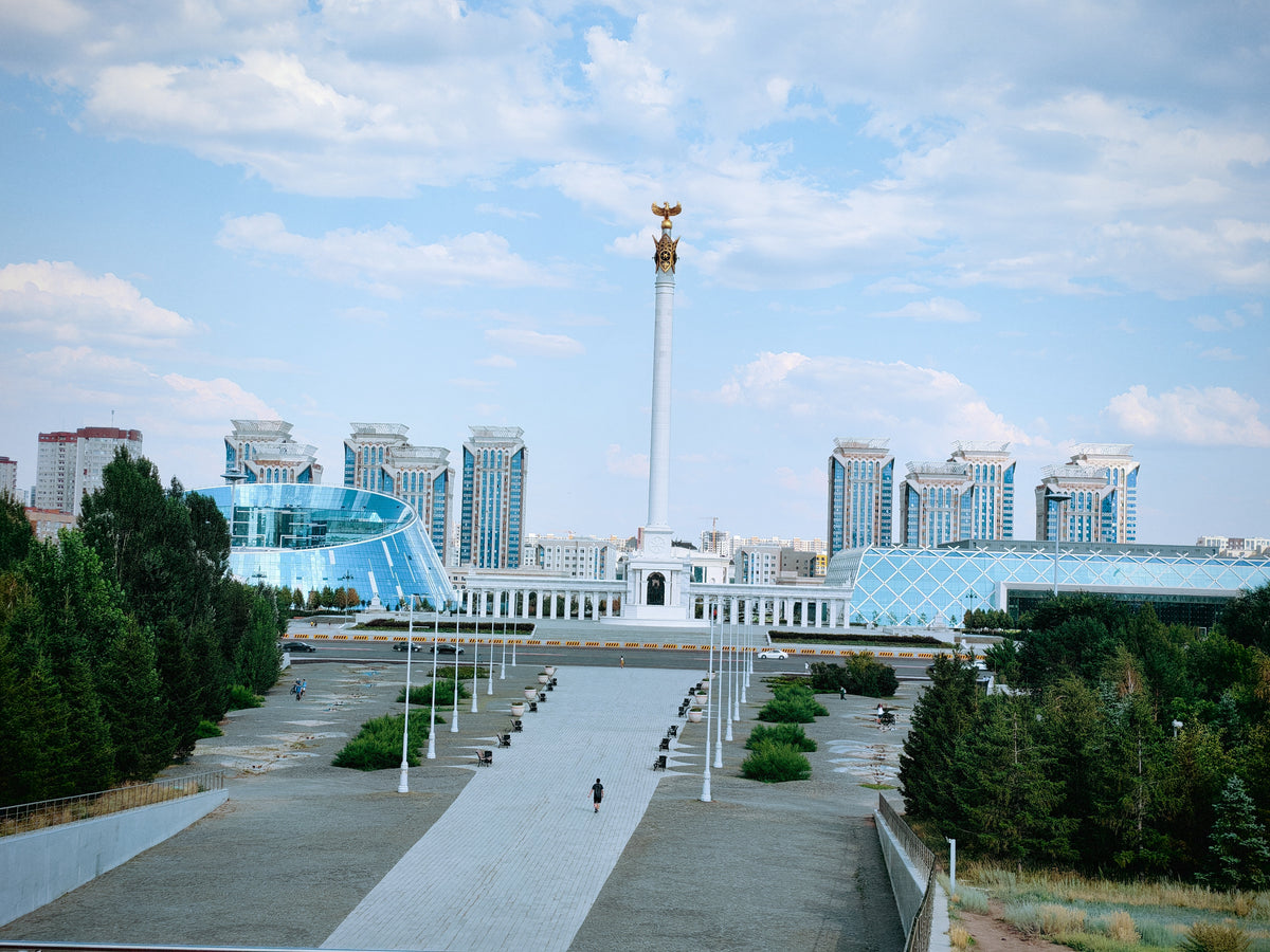 Tágas városi boulevard Asztanában, modern épületekkel és emlékművel.