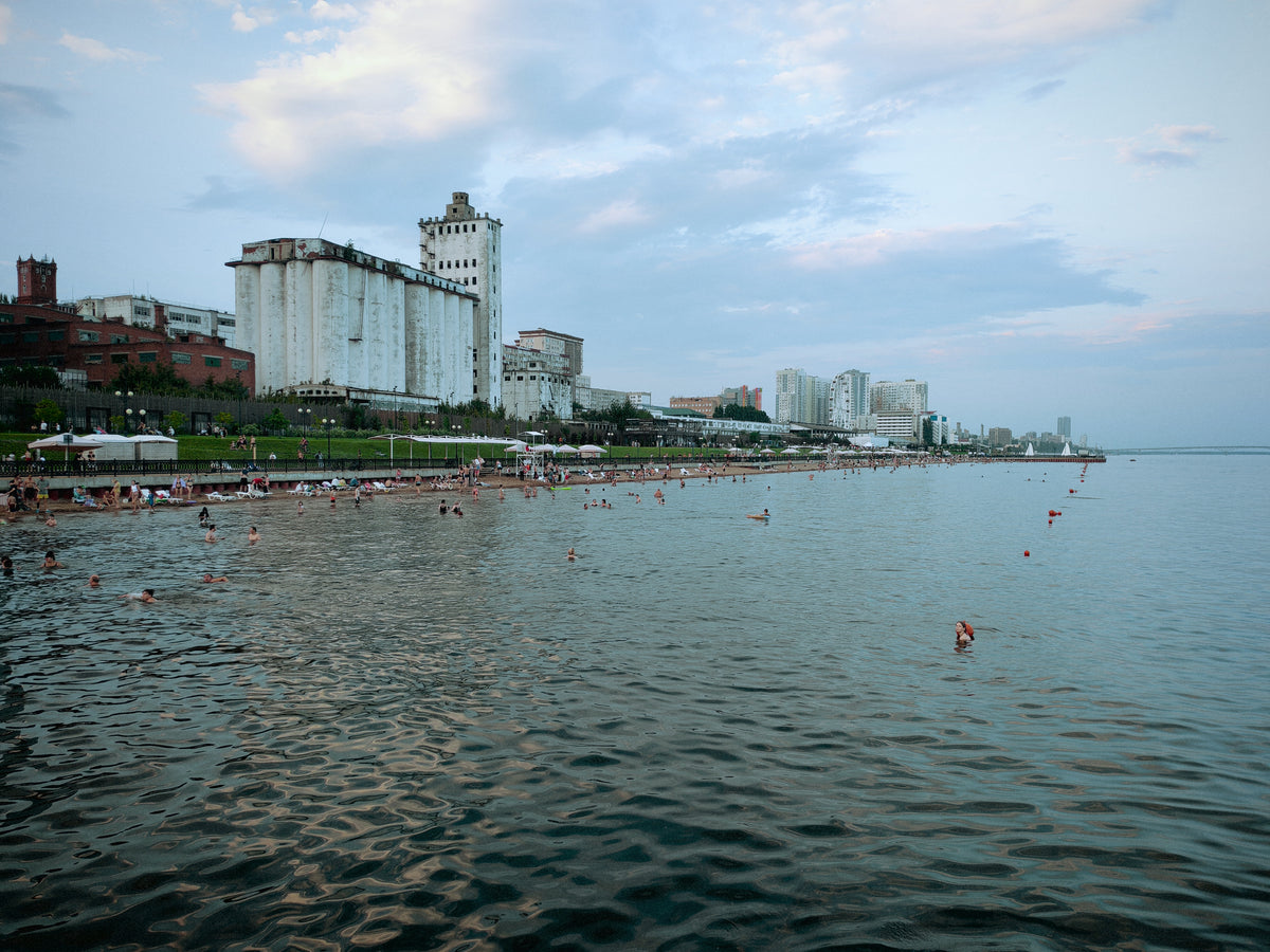 Városi strand és fürdőzők egy széles vízparton a visszaút során.