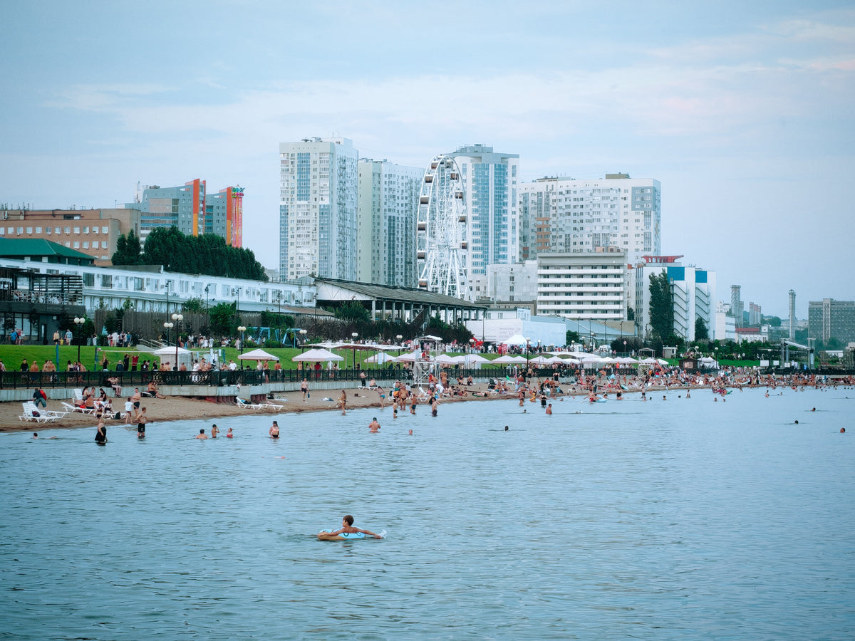 Nyüzsgő városi strand modern épületekkel a háttérben.