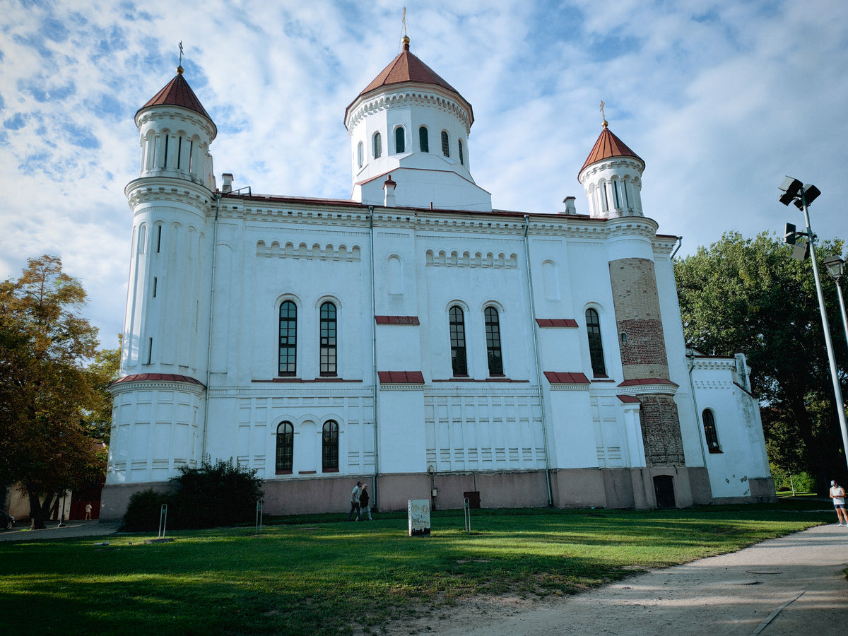 Fehér ortodox templom Vilnius zöld óvárosi környezetében.